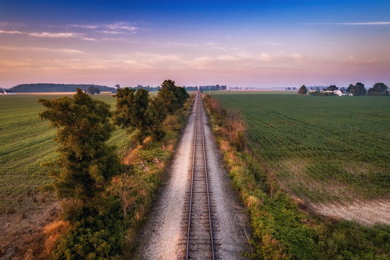 The railroad track going between the crops of corn and soybeans on a summer morning in Ohio.