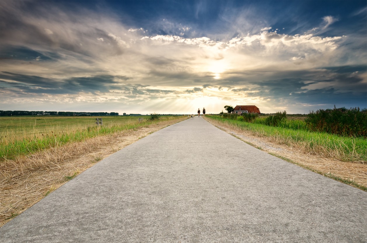 couple walking on path over dramatic sky in summer