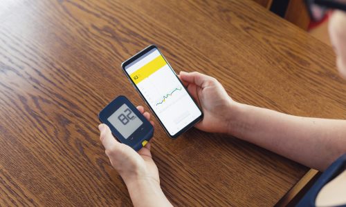 Woman comparing result of glucose level check on the traditional glucometer and on the mobile phone read from modern technology remote sensor Woman comparing result of glucose level check on the traditional glucometer and on the mobile phone read from modern technology remote sensor
